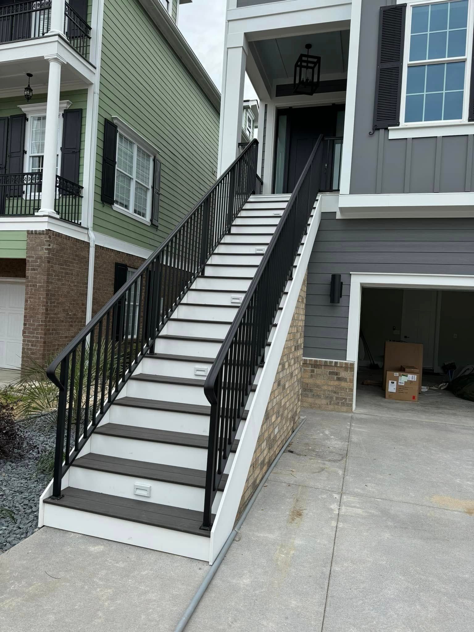 Exterior staircase with black railings and white steps leading to a second-floor entrance between two buildings