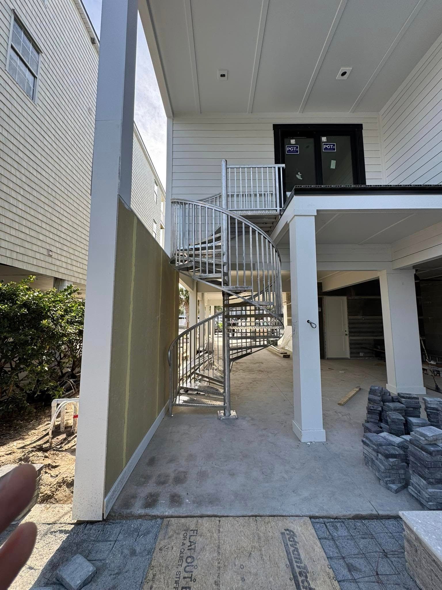 Outdoor stairway and covered patio beside a modern building with a gated entry and stone landscaping.
