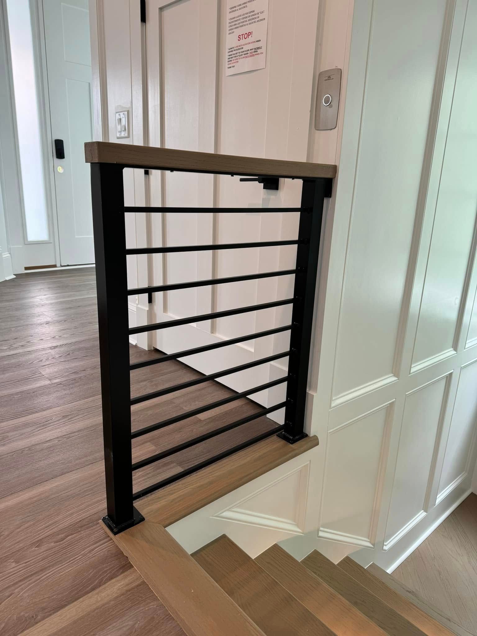Black metal stair railing beside carpeted stairs in a hallway with white walls and doors