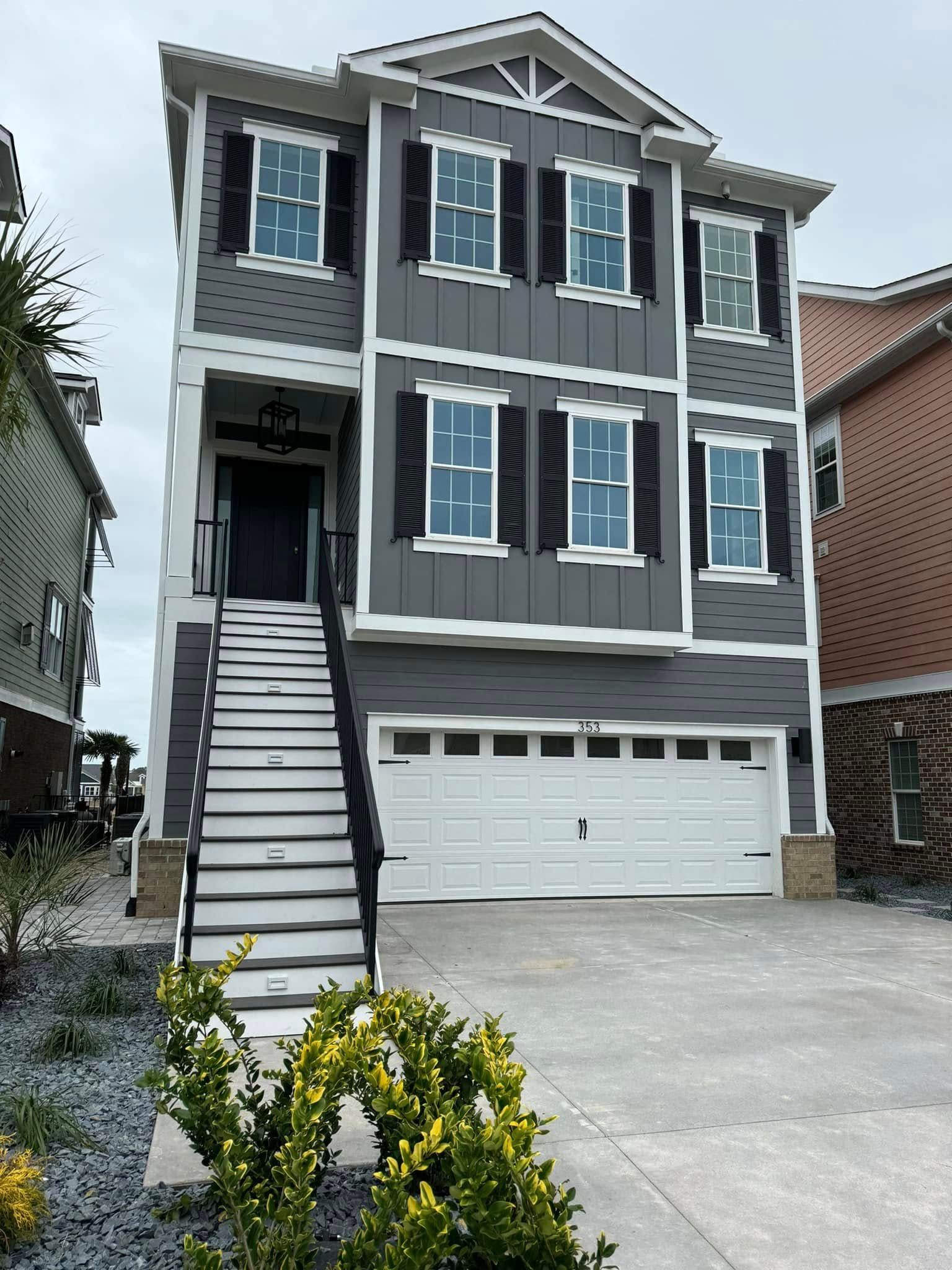 Gray two-story house with white trim, front stairs, and a double garage on a driveway