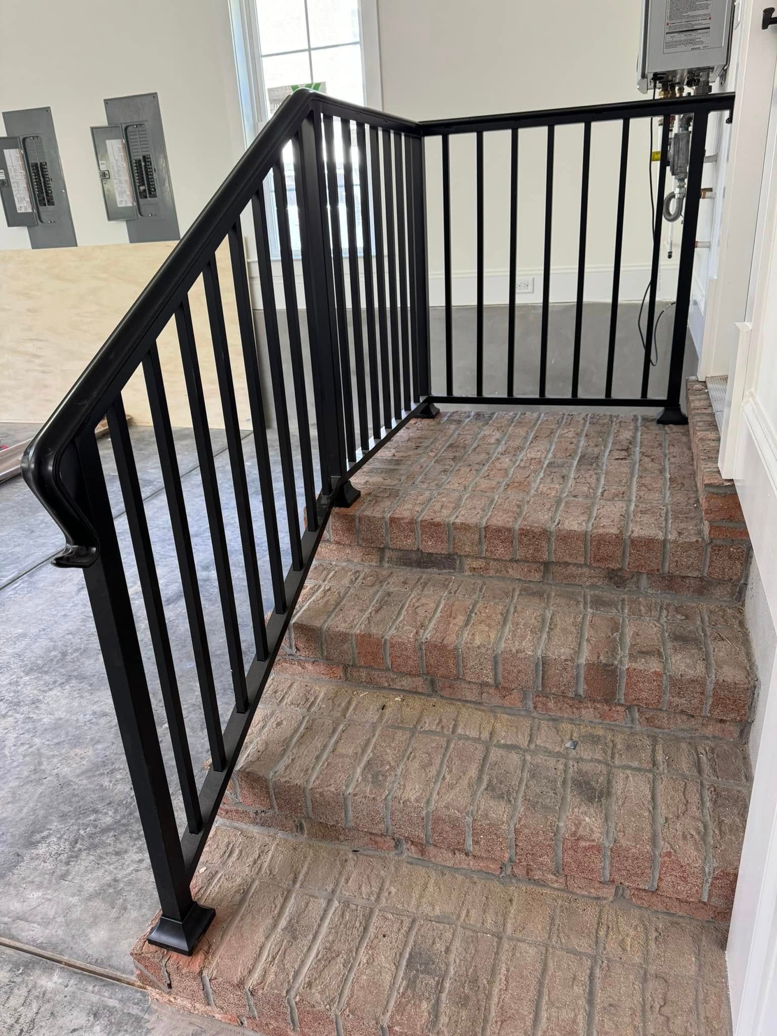 Black metal staircase railing beside a carpeted landing in an indoor hallway