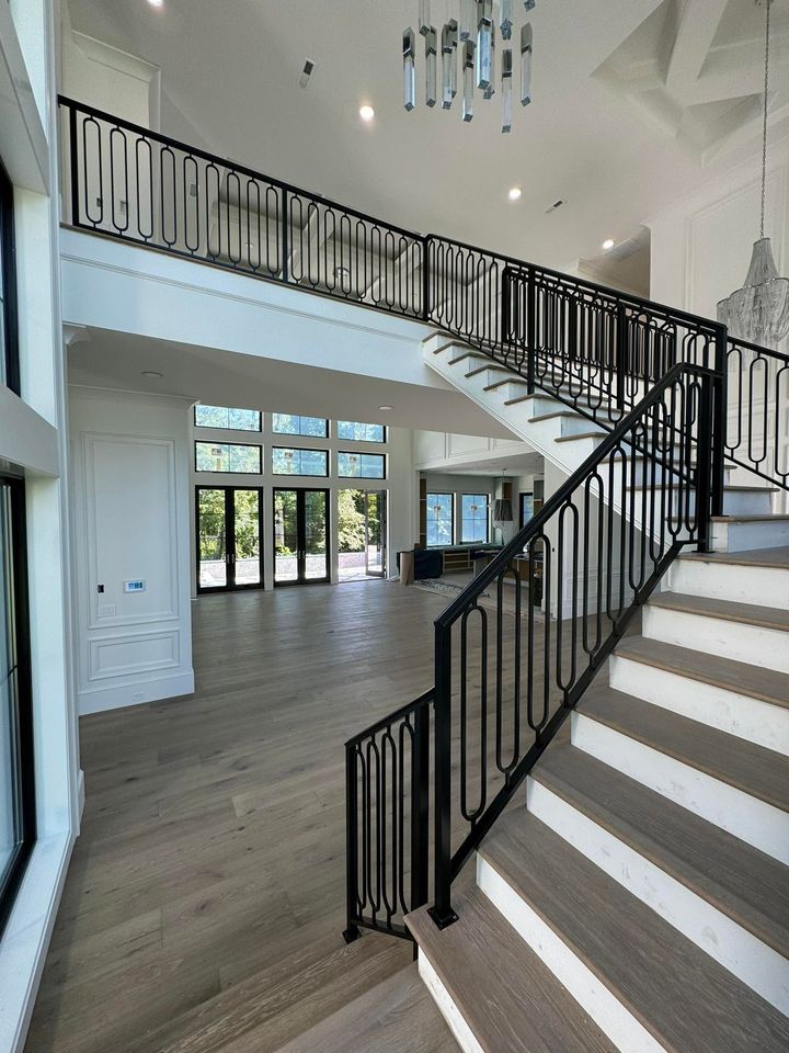 Bright modern foyer with floating staircase, black railings, high ceiling, and large windows