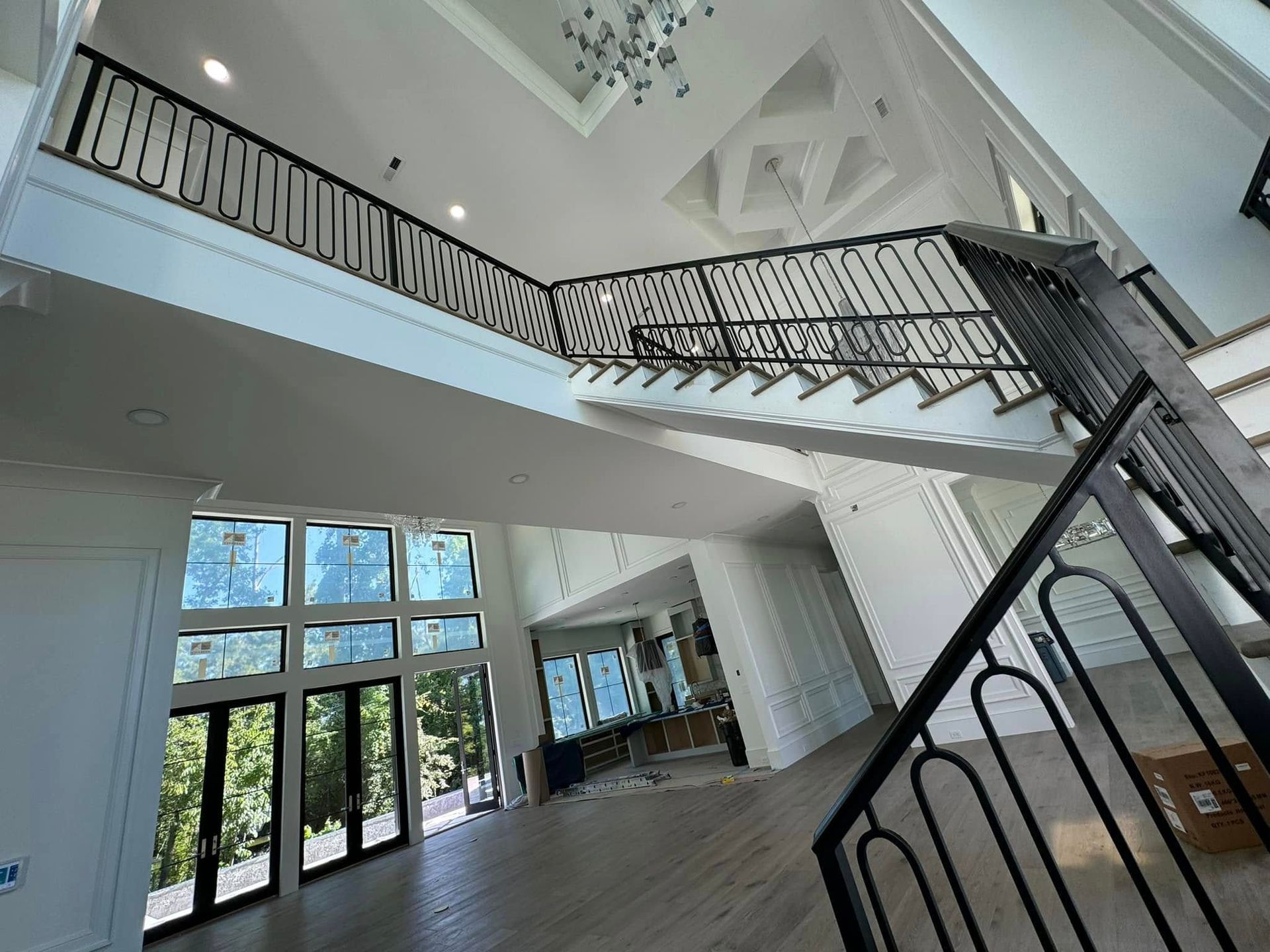 Bright modern atrium with white staircase, black railings, and large windows letting in daylight