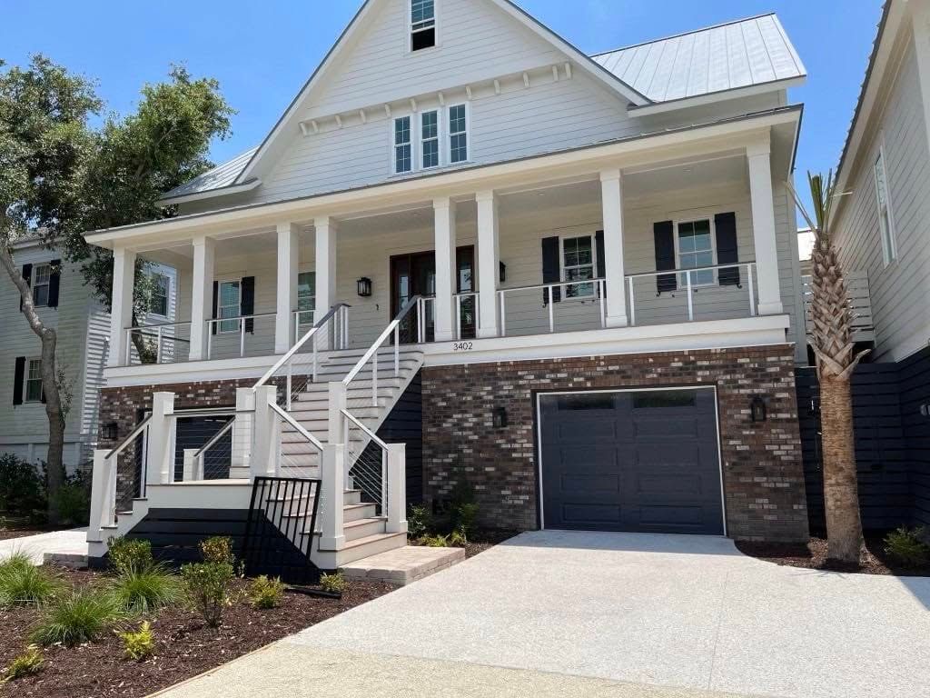 White two-story house with front porch, stone accents, staircase, and attached garage