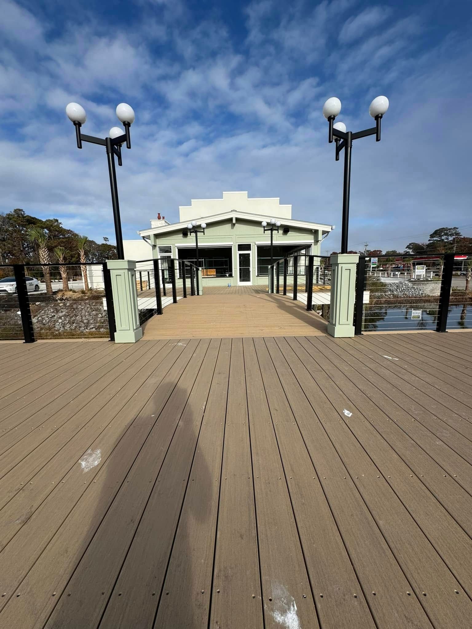 Wooden boardwalk leading to a white pavilion by the water under a blue sky