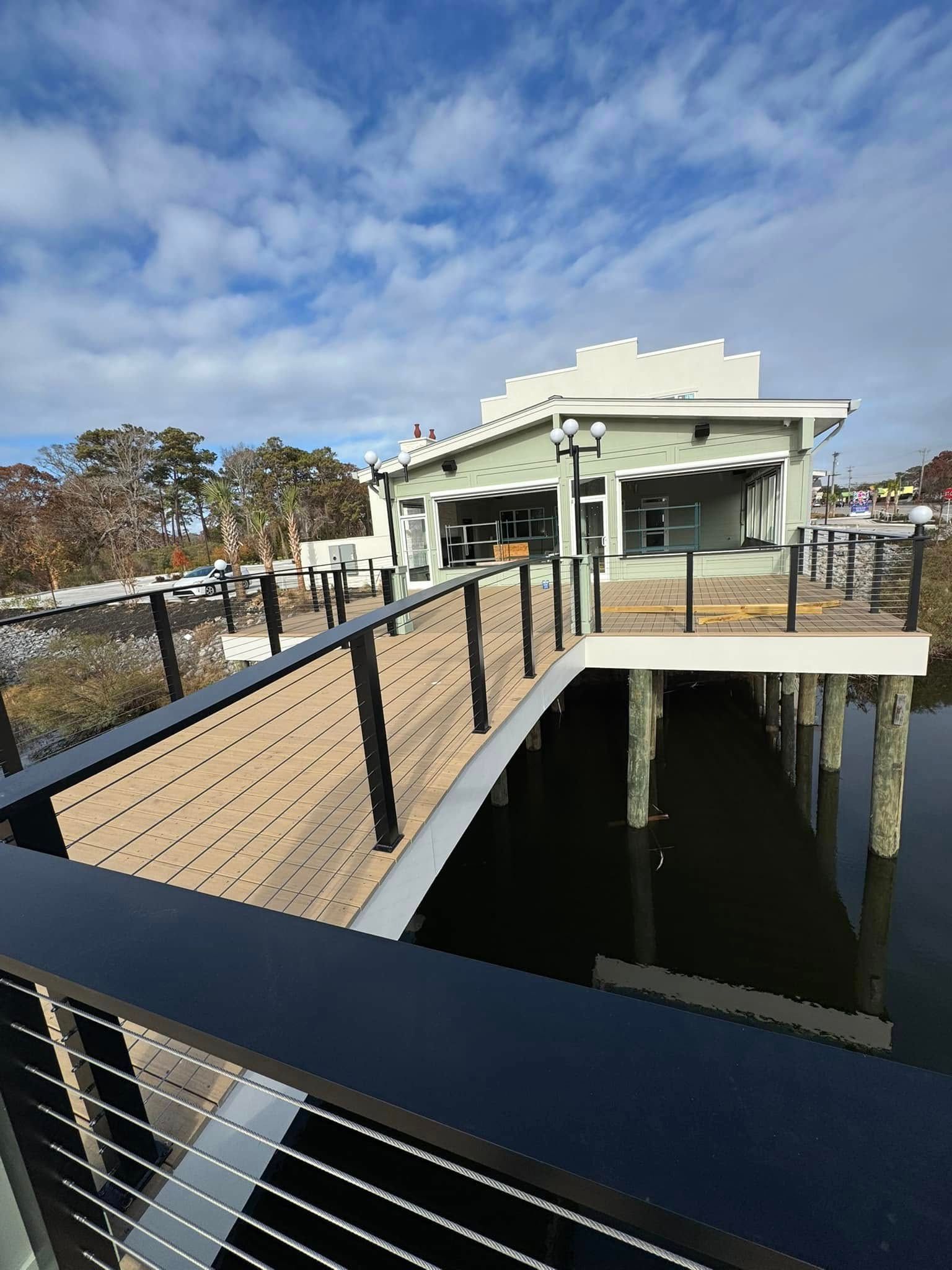 Accessible boardwalk leading to a white waterfront building under a partly cloudy sky