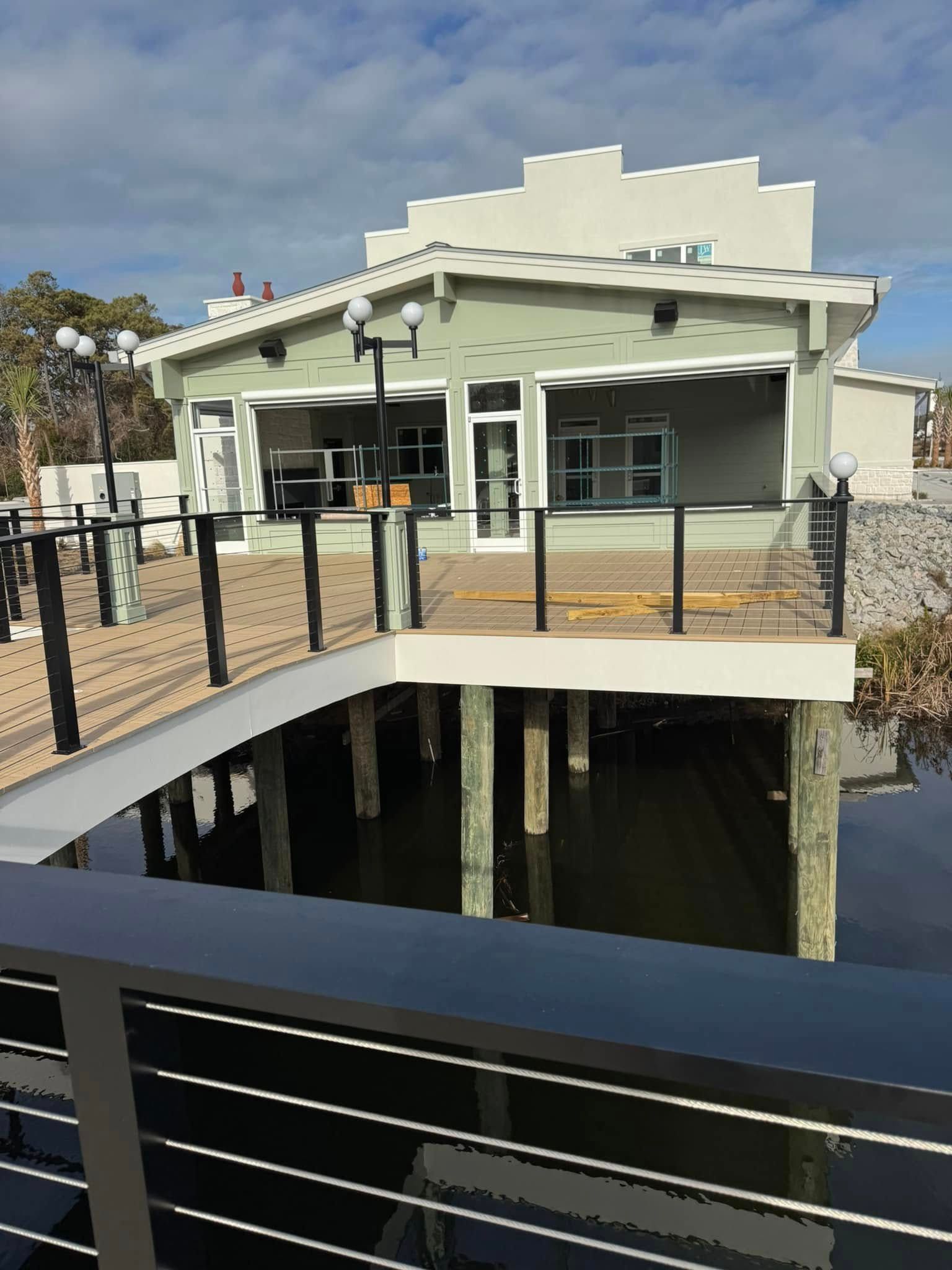 Modern waterfront house with a black bridge railing and dock over water