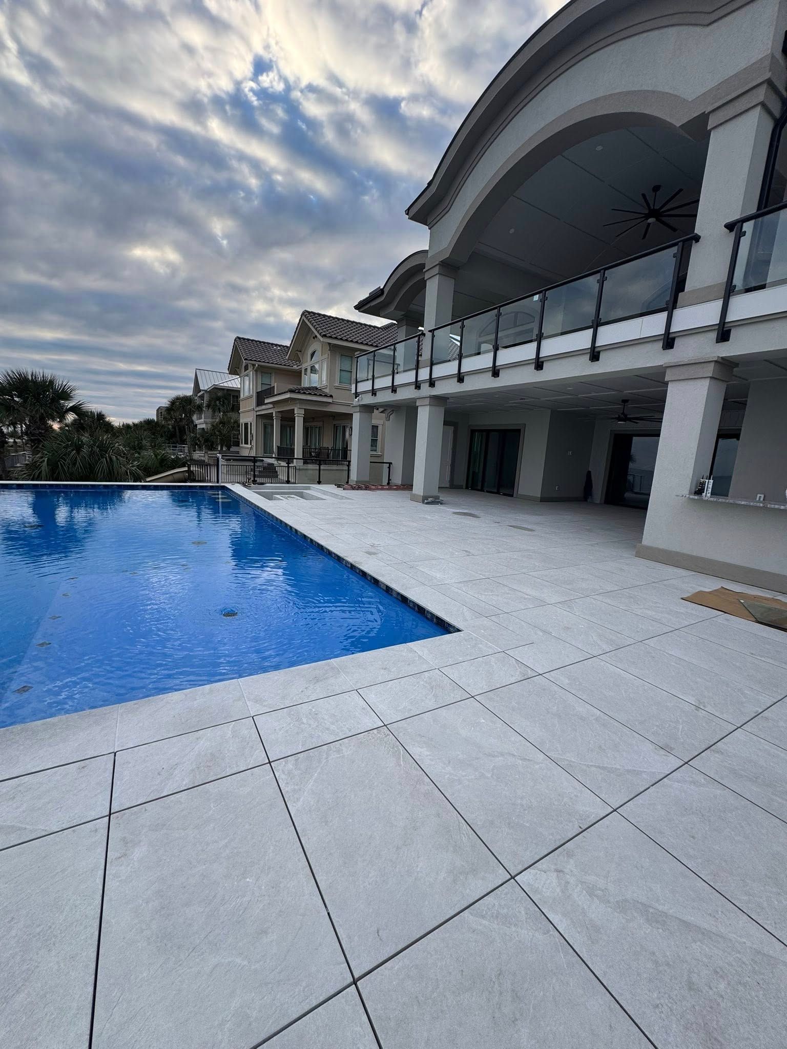 Luxury hotel pool beside a white resort building under a cloudy sky