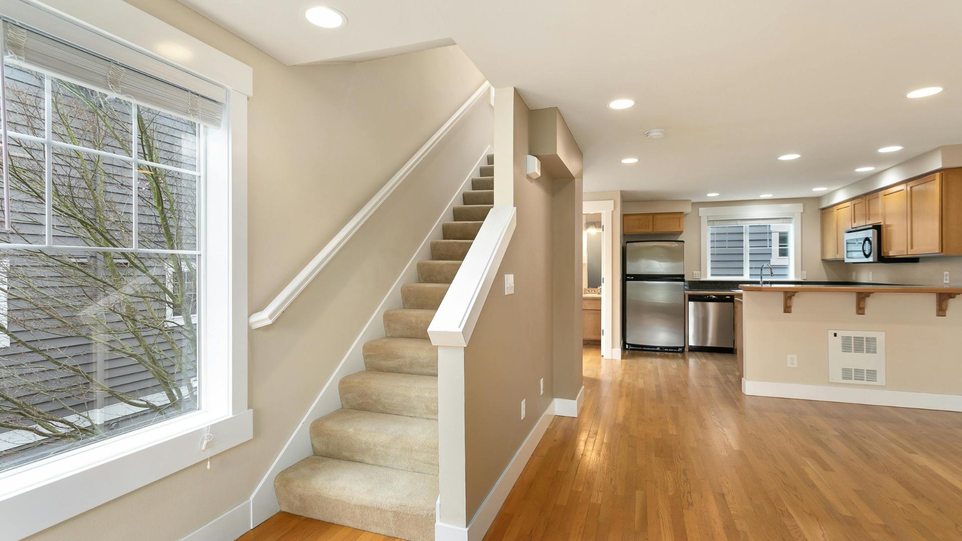 Empty beige hallway with a doorway, wall signs, and a polished gray floor.