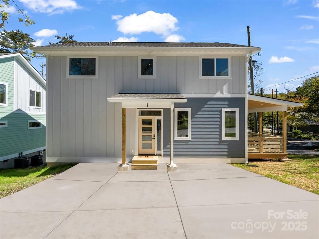 Two-story house with light blue and gray siding, small porch. Concrete driveway.