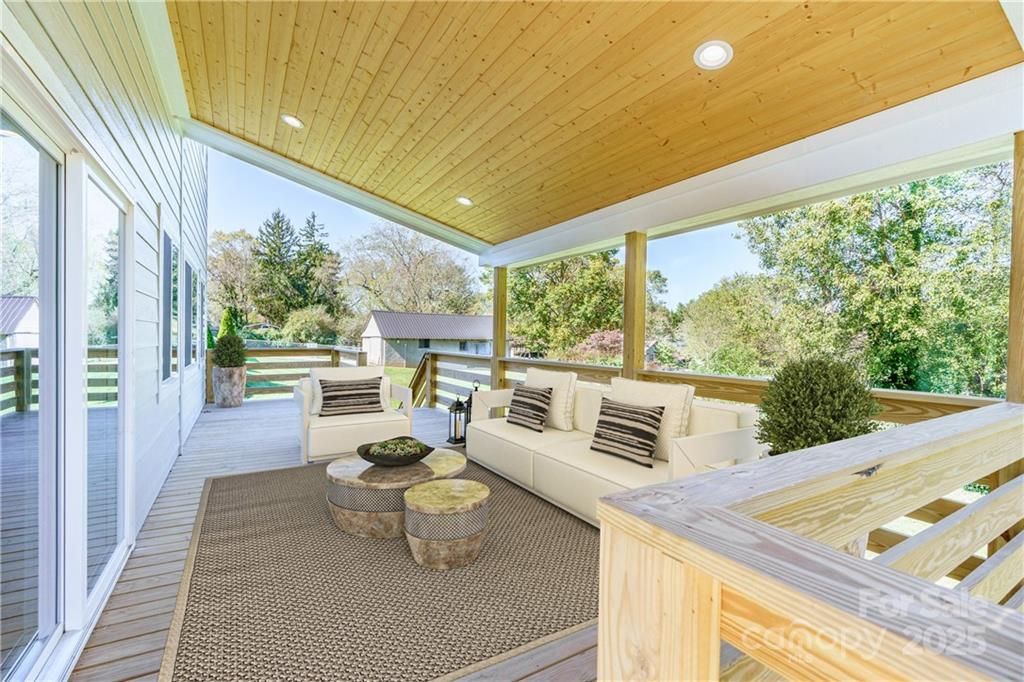 Covered outdoor patio with white seating, patterned rug, wood ceiling, and garden views