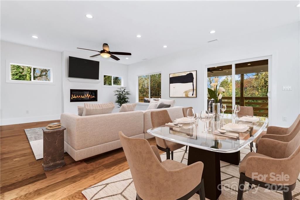 Bright open-concept living and dining room with neutral decor, wood floors, and sliding glass doors to a patio.