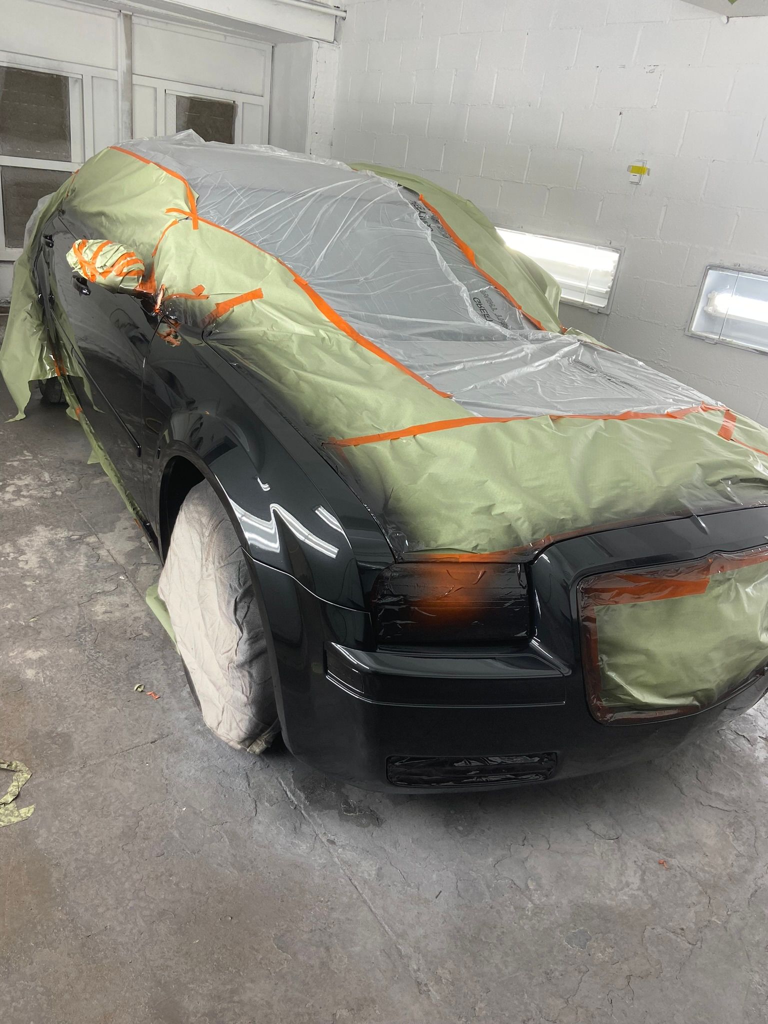 A Black Car Is Covered in Plastic Wrap in A Garage — Chicago, IL — Ecuamex Autobody Inc.