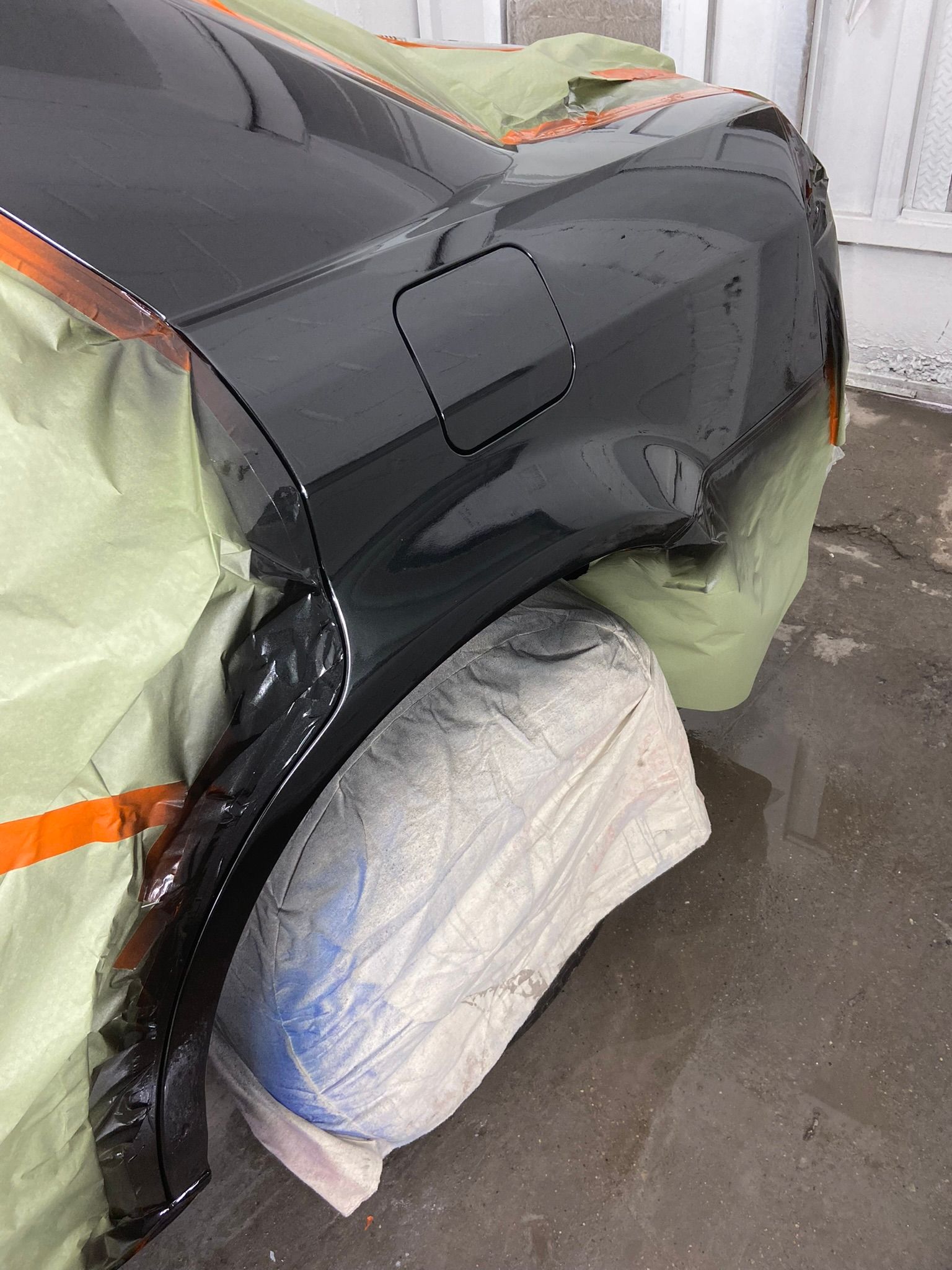 A Black Car Is Being Painted in A Garage — Chicago, IL — Ecuamex Autobody Inc.