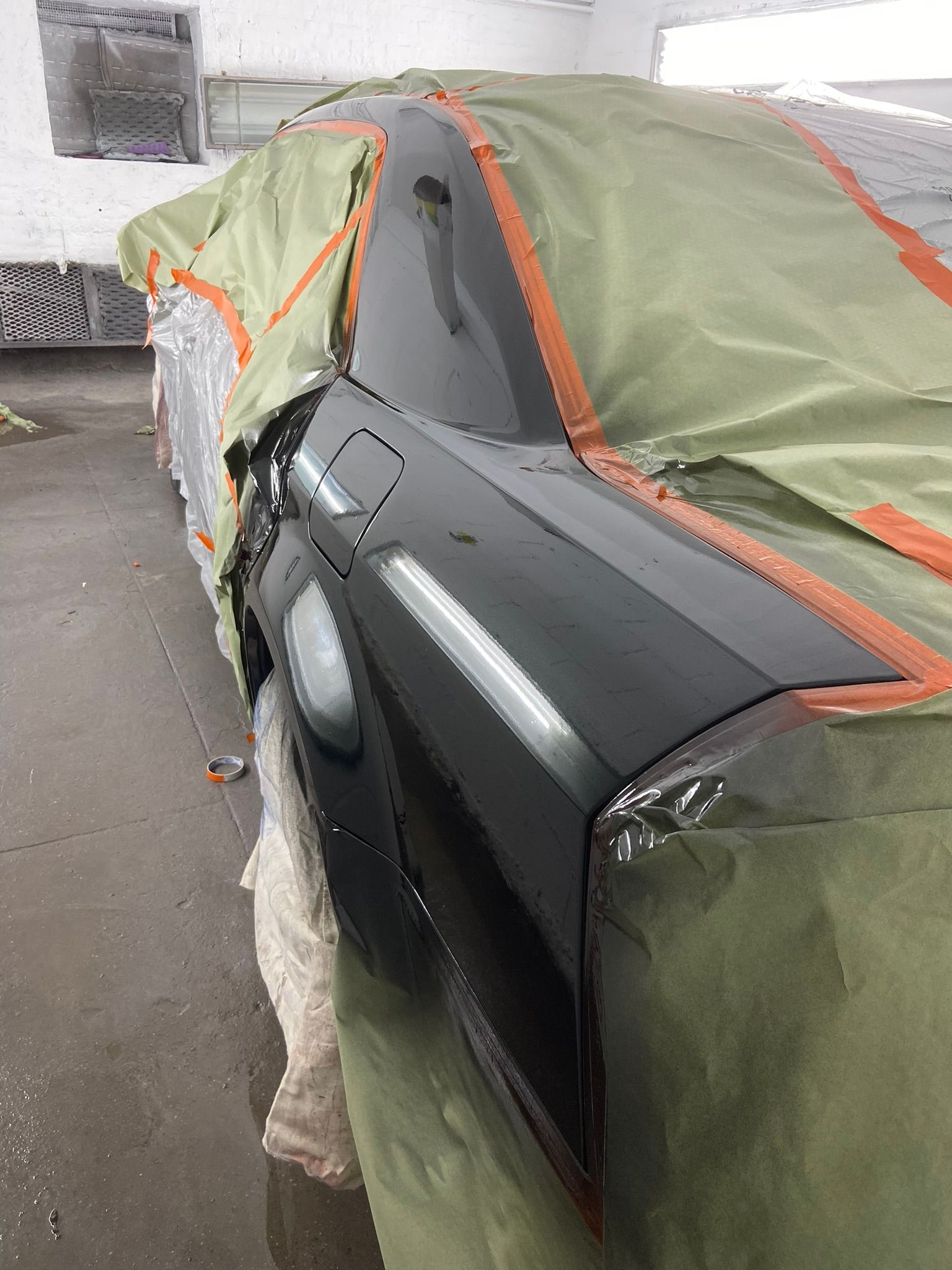 A Black Car Is Covered in A Green Tarp in A Garage — Chicago, IL — Ecuamex Autobody Inc.