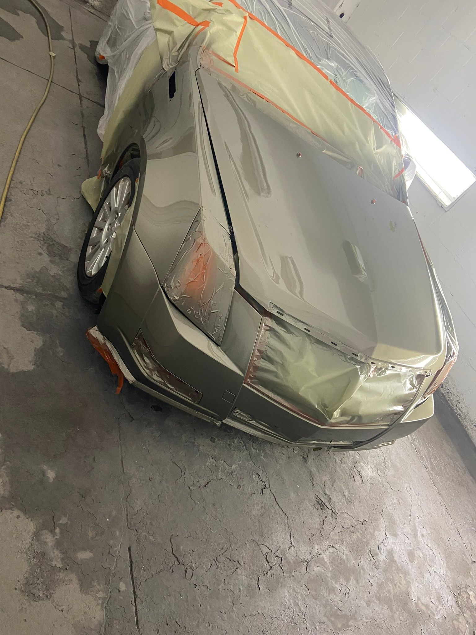 A Car Is Sitting on The Ground in A Garage Covered in Plastic Wrap — Chicago, IL — Ecuamex Autobody Inc.