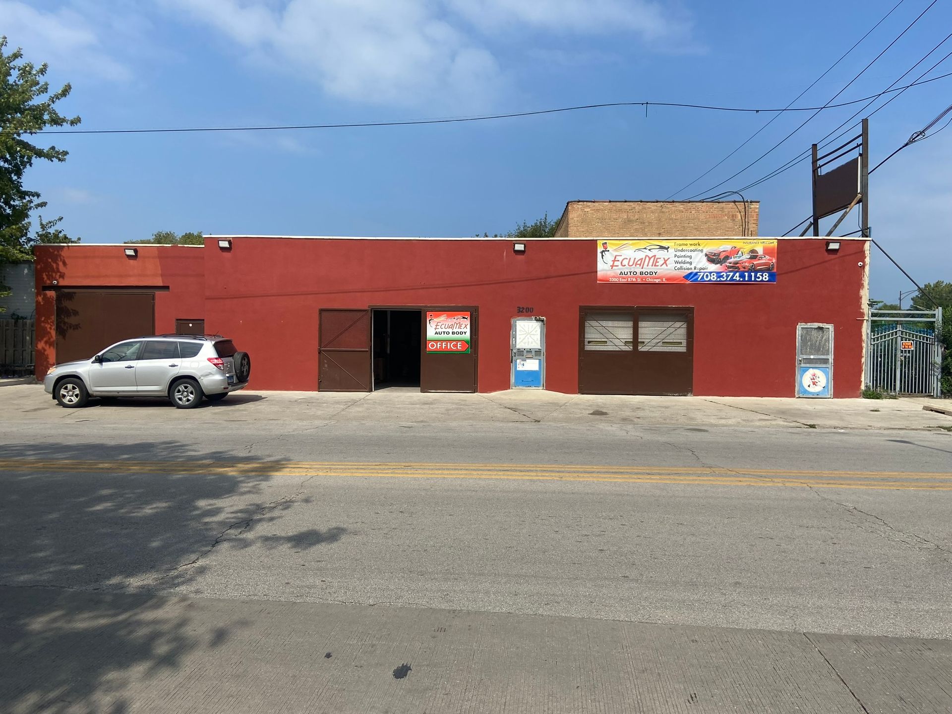 A White Suv Is Parked in Front of A Red Building — Chicago, IL — Ecuamex Autobody Inc.