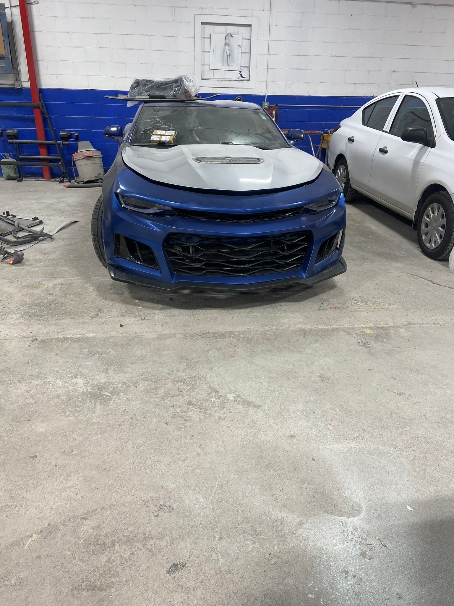 A Blue Car Is Parked in A Garage Next to A White Car — Chicago, IL — Ecuamex Autobody Inc.