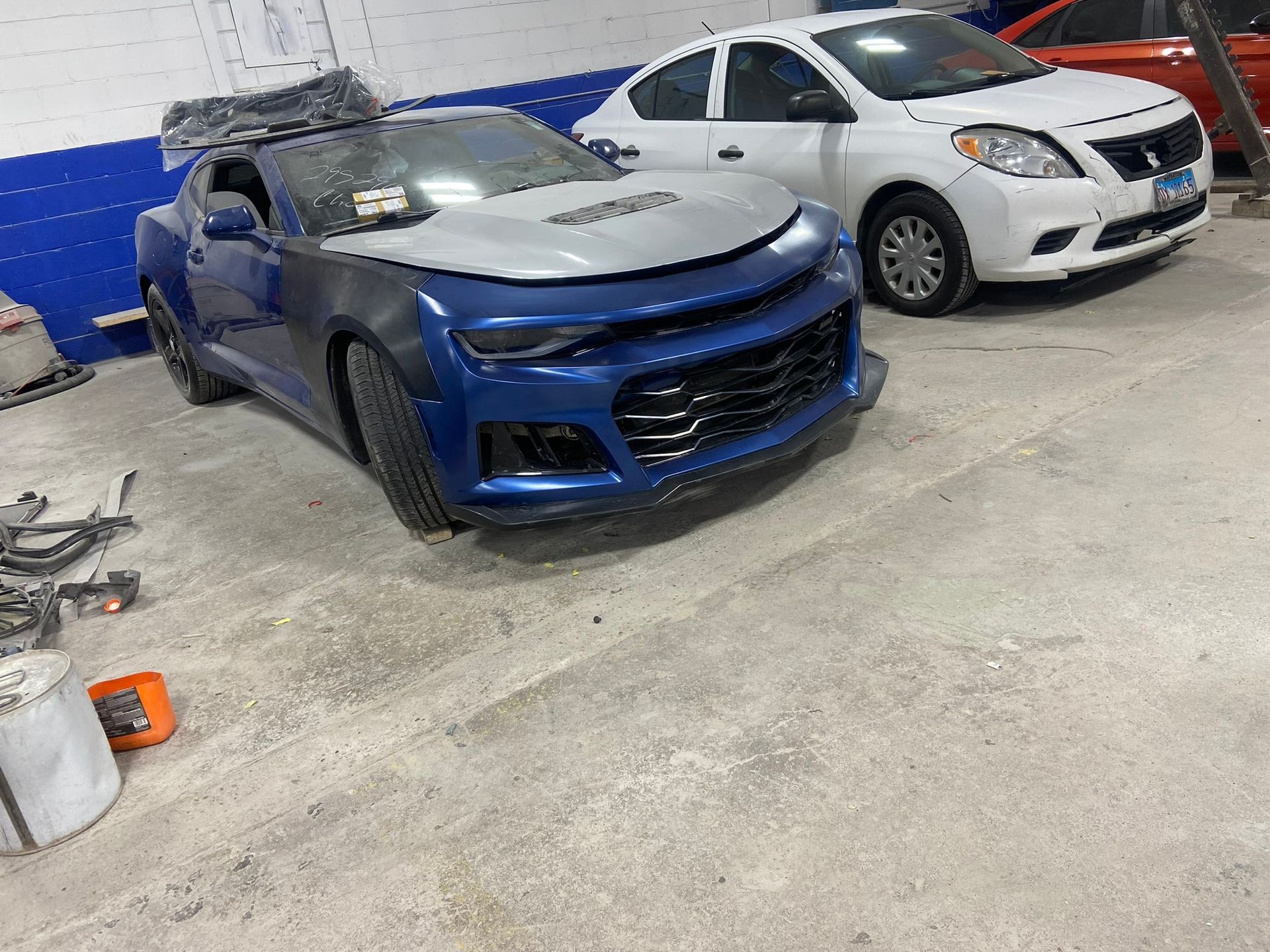A Blue Car Is Parked Next to A White Car in A Garage — Chicago, IL — Ecuamex Autobody Inc.