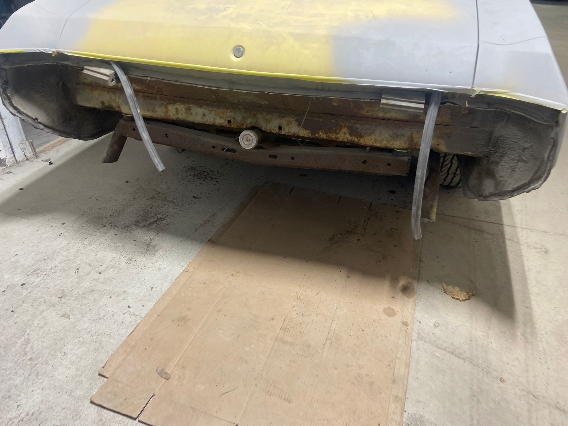 A Yellow Car Is Sitting on A Cardboard Box in A Garage — Chicago, IL — Ecuamex Autobody Inc.