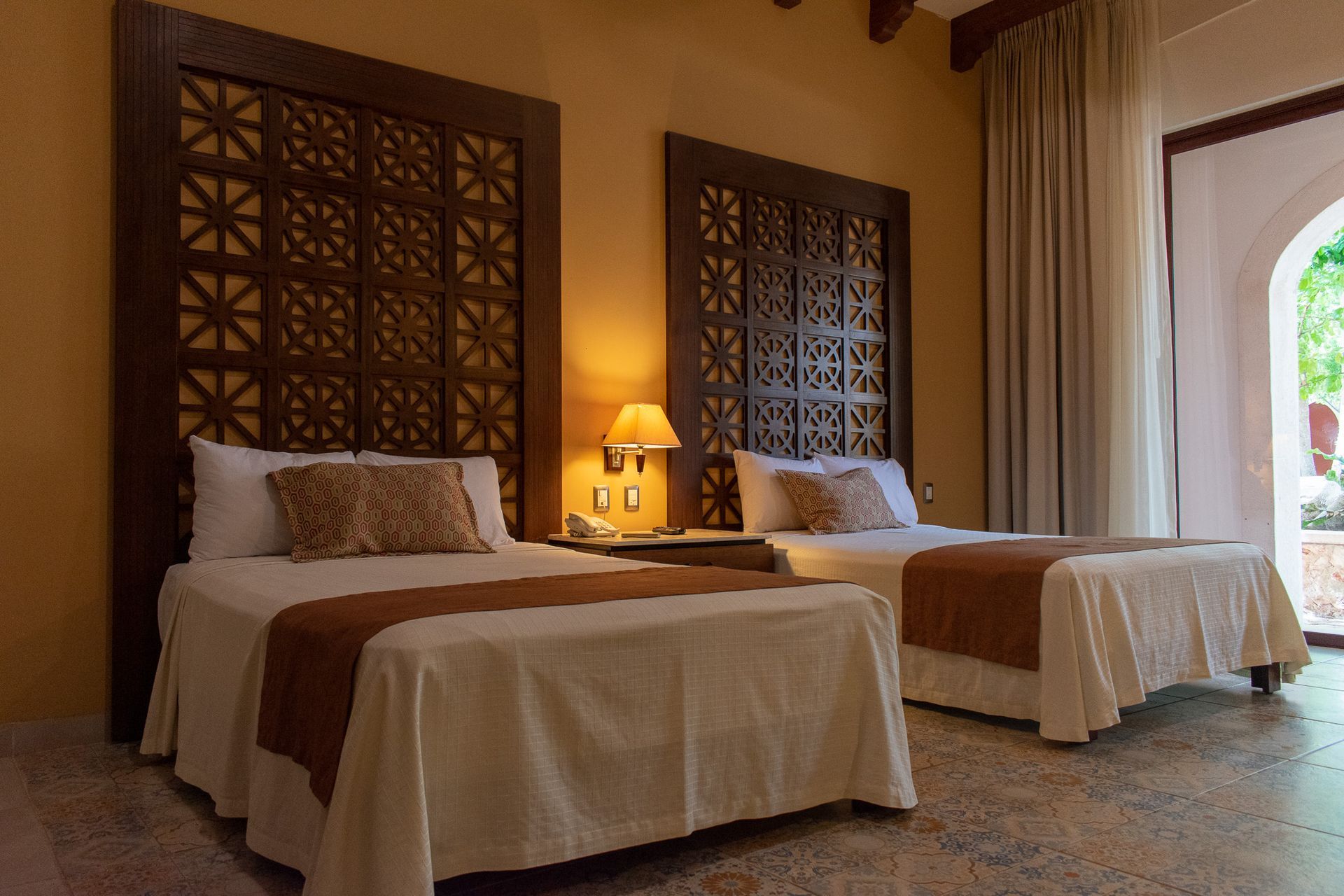 Una habitación de hotel con dos camas y cabecero de madera.