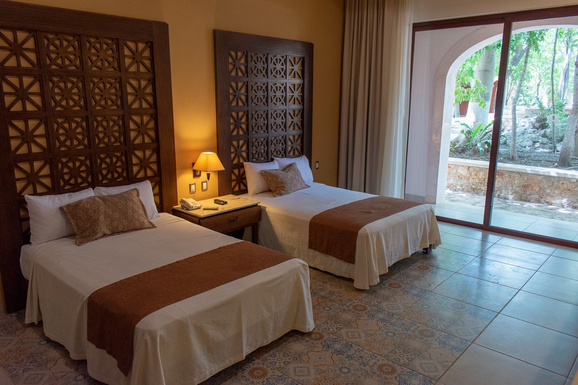 Una habitación de hotel con dos camas y una puerta corrediza de cristal.