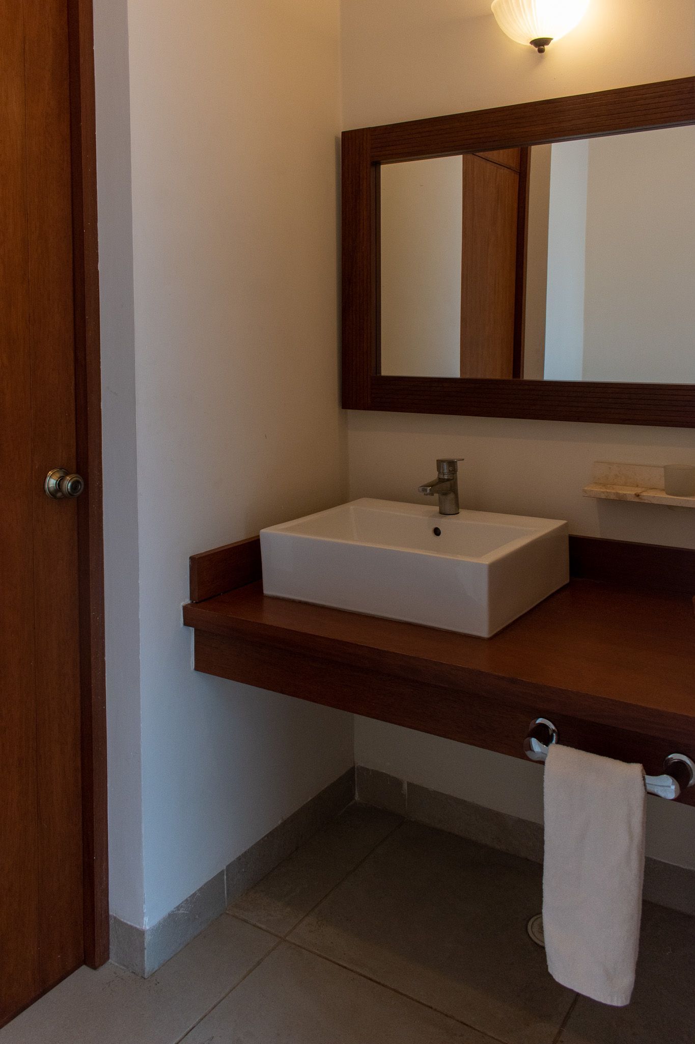 Un baño con lavabo, espejo y toalla colgada en la pared.