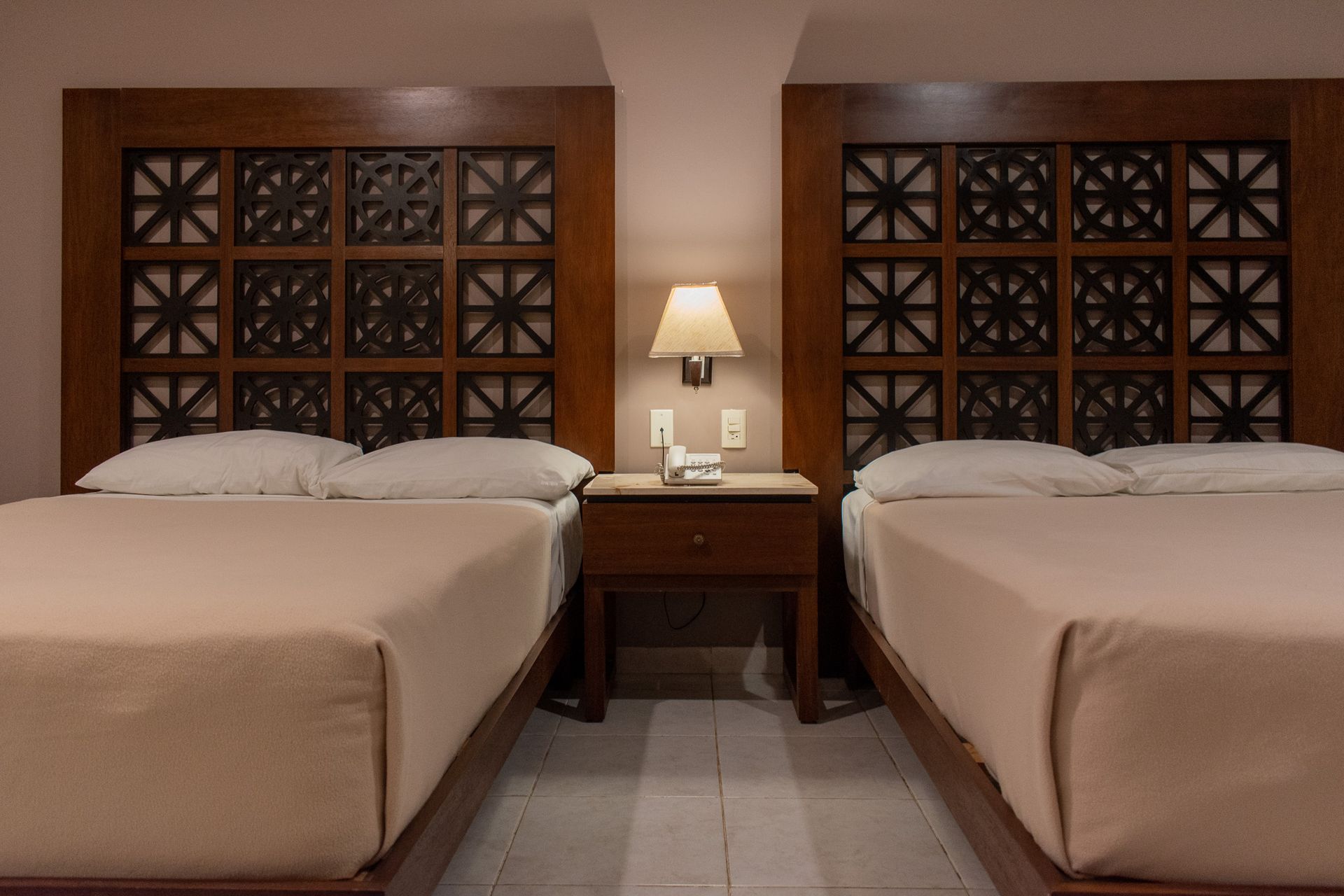 Una habitación de hotel con dos camas, una mesita de noche y una lámpara.