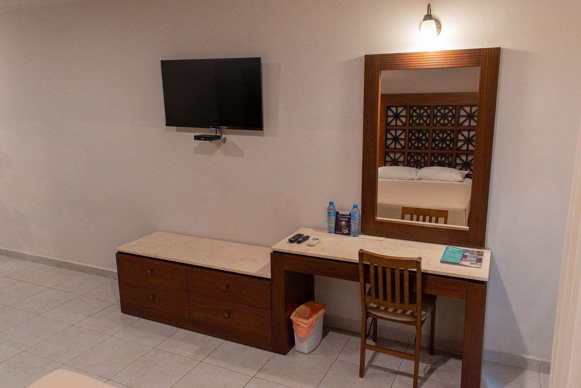 Una habitación de hotel con escritorio, silla, televisión y espejo.