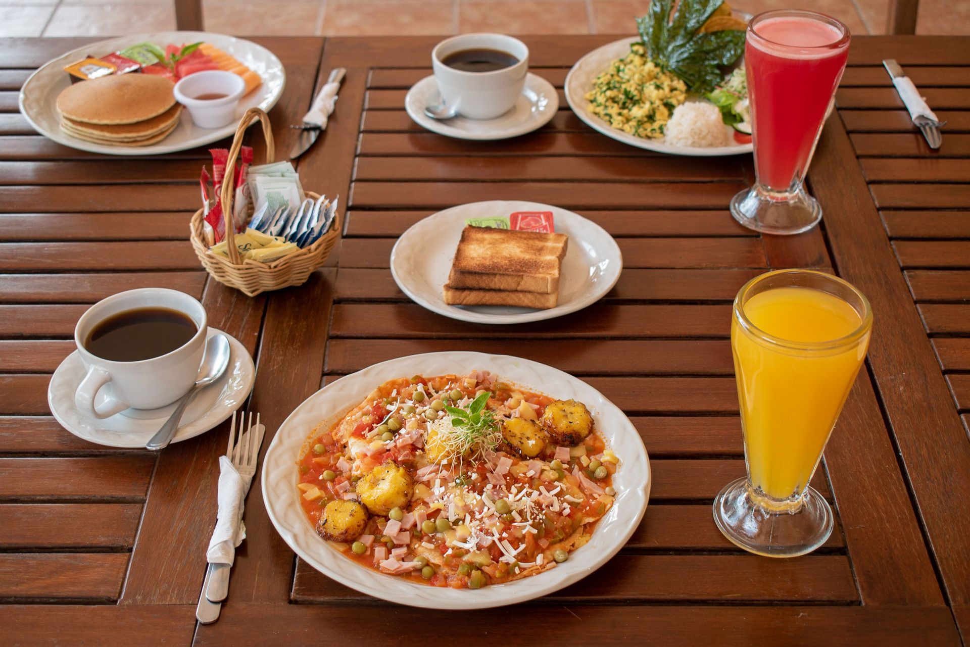 Una mesa de madera cubierta con platos de comida y bebidas.
