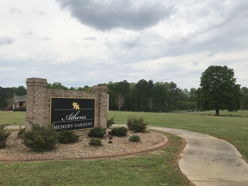 A sign that says welcome is in the middle of a grassy field