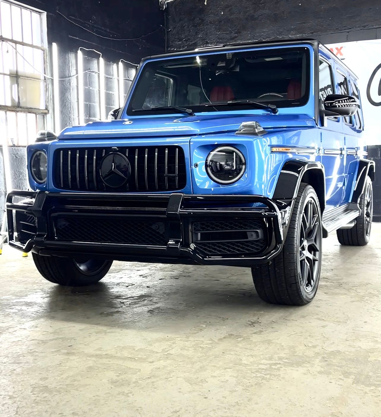 A blue jeep is parked in a garage.
