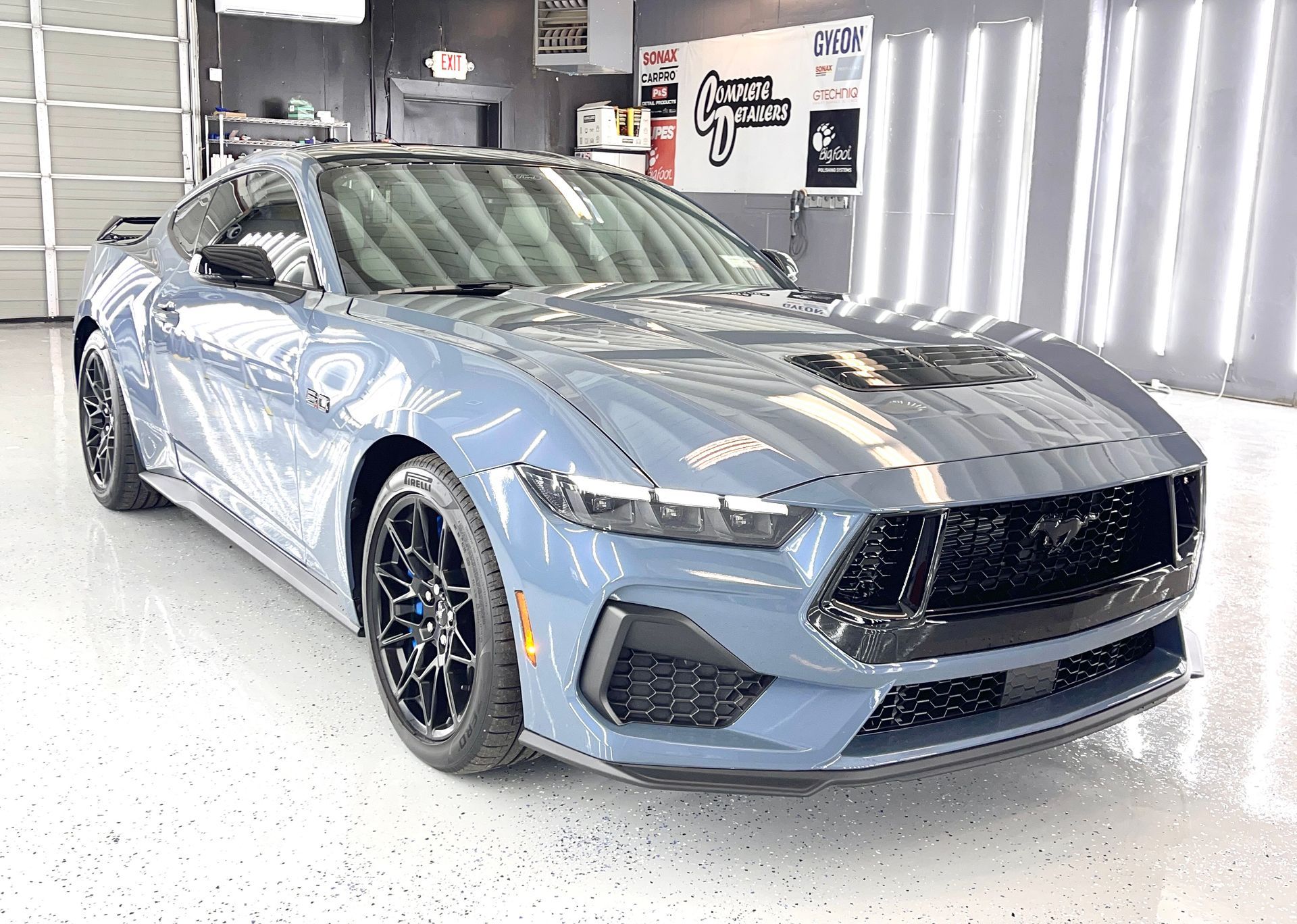 A blue ford mustang is parked in a garage.