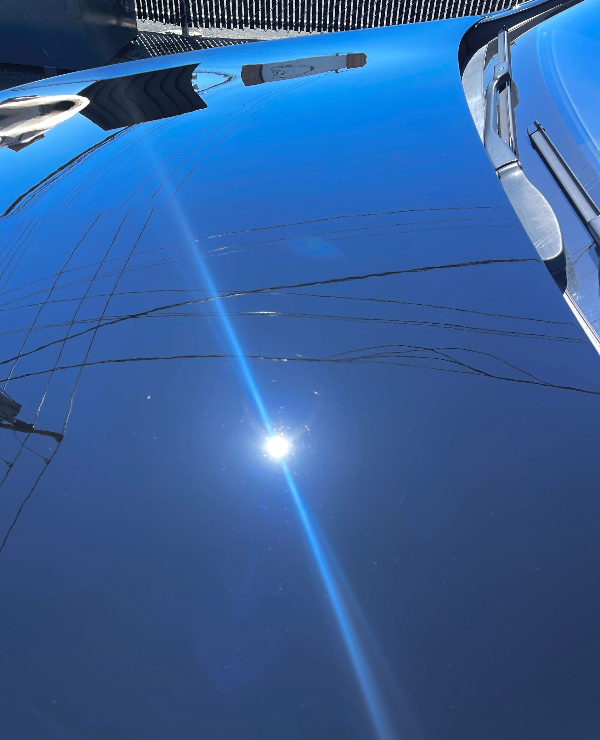 The sun is reflected in the hood of a car