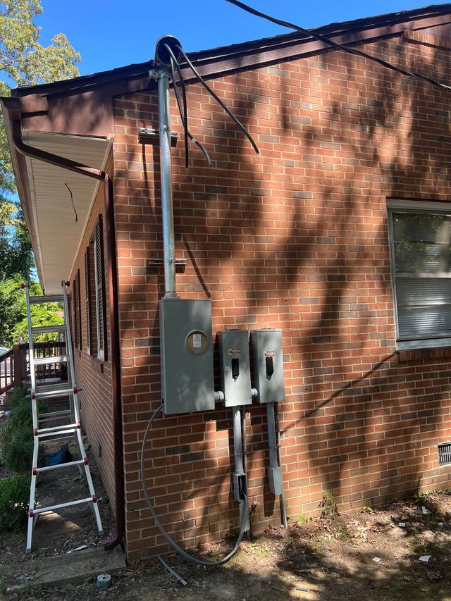 Brick building exterior with electrical meters, conduit, and a ladder leaning against the wall
