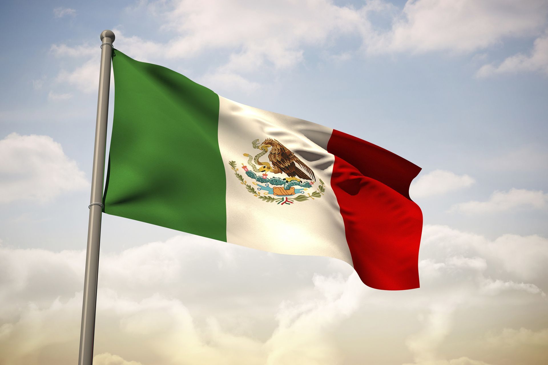 Una bandera mexicana ondea en el viento contra un cielo nublado