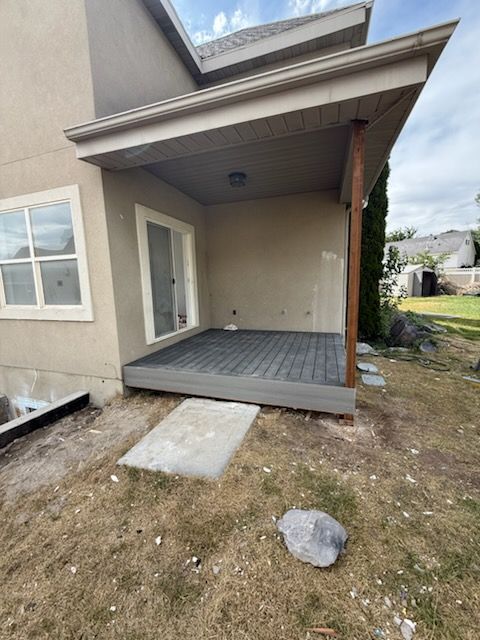 Backyard patio with gray flooring and tan walls, under a roof.