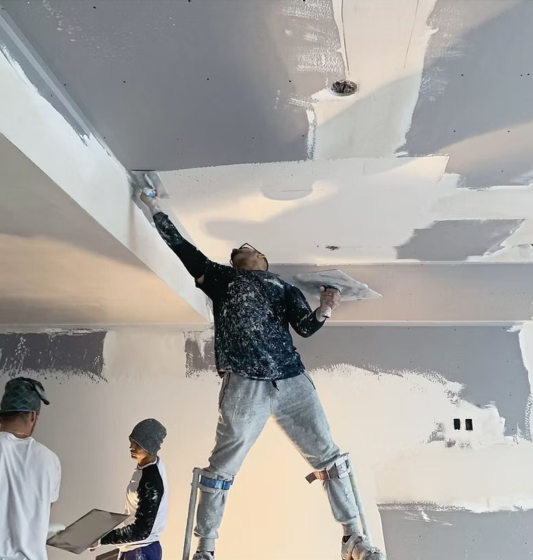 Workers painting and patching a ceiling during interior drywall repair.