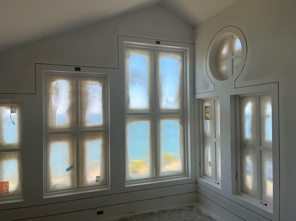 Bright white room with multiple windows and a round window opening, letting in soft daylight.