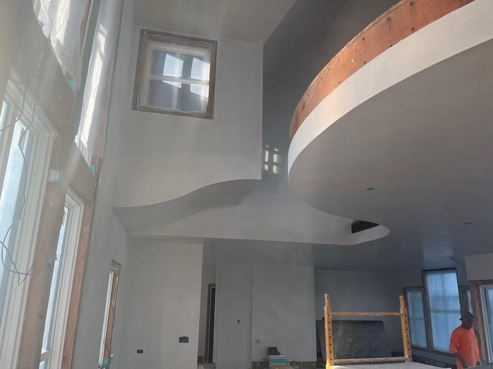 Modern interior with curved mezzanine, tall windows, and a small upper window.