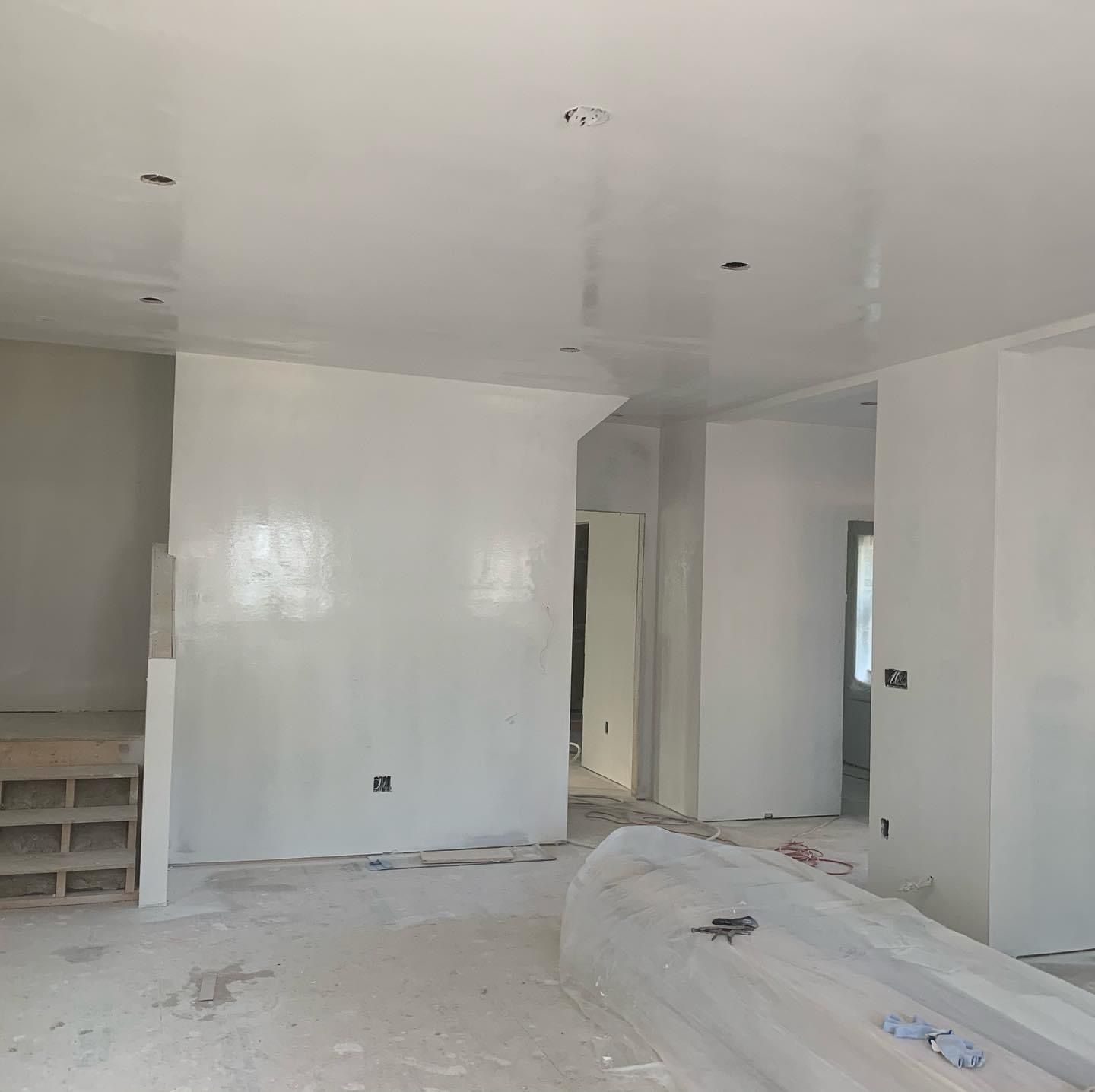 White unfinished room under construction with built-in shelves, doorway, and debris on the floor.