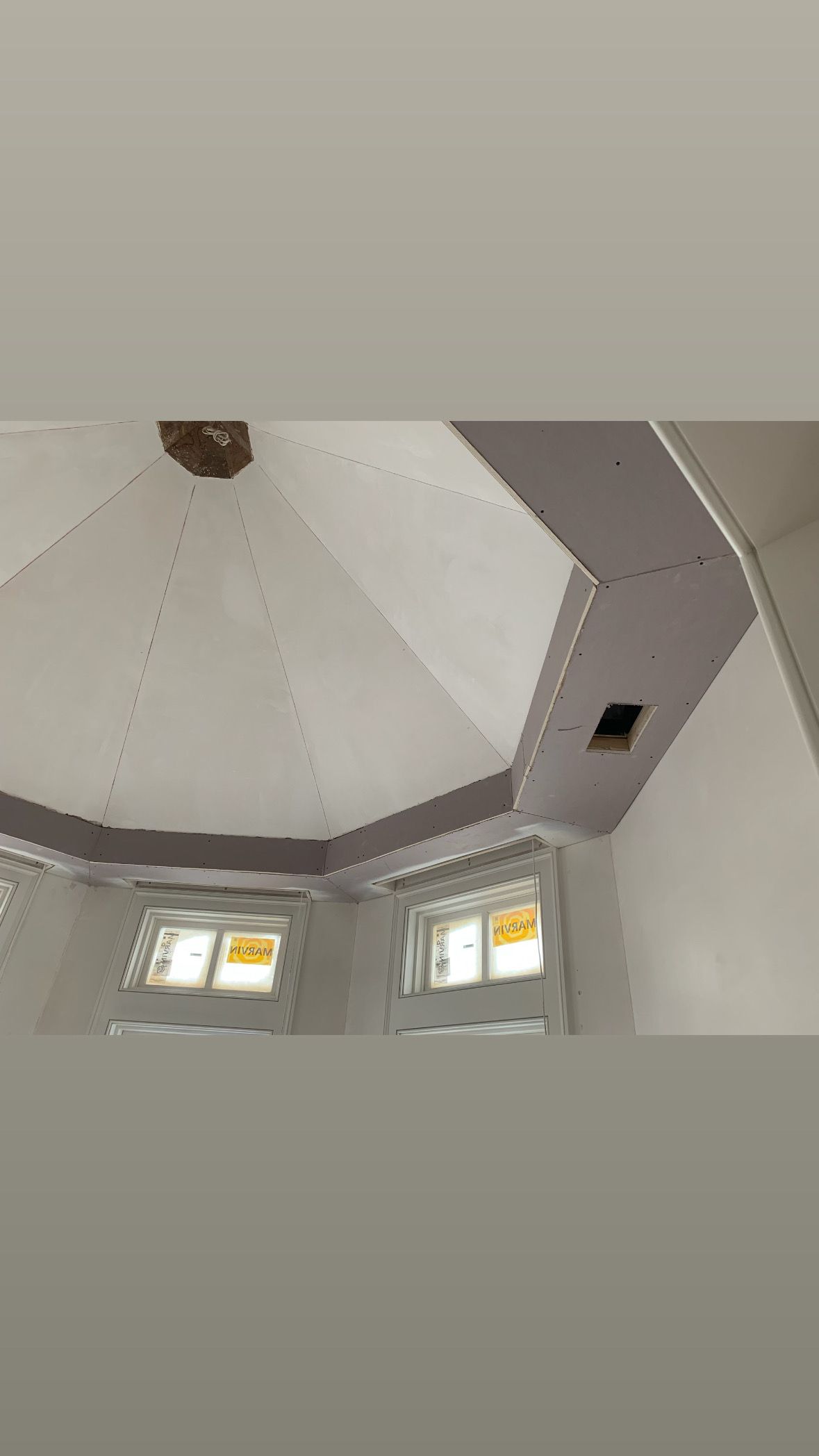 Interior of a room with a high octagonal ceiling, small windows, and white walls.