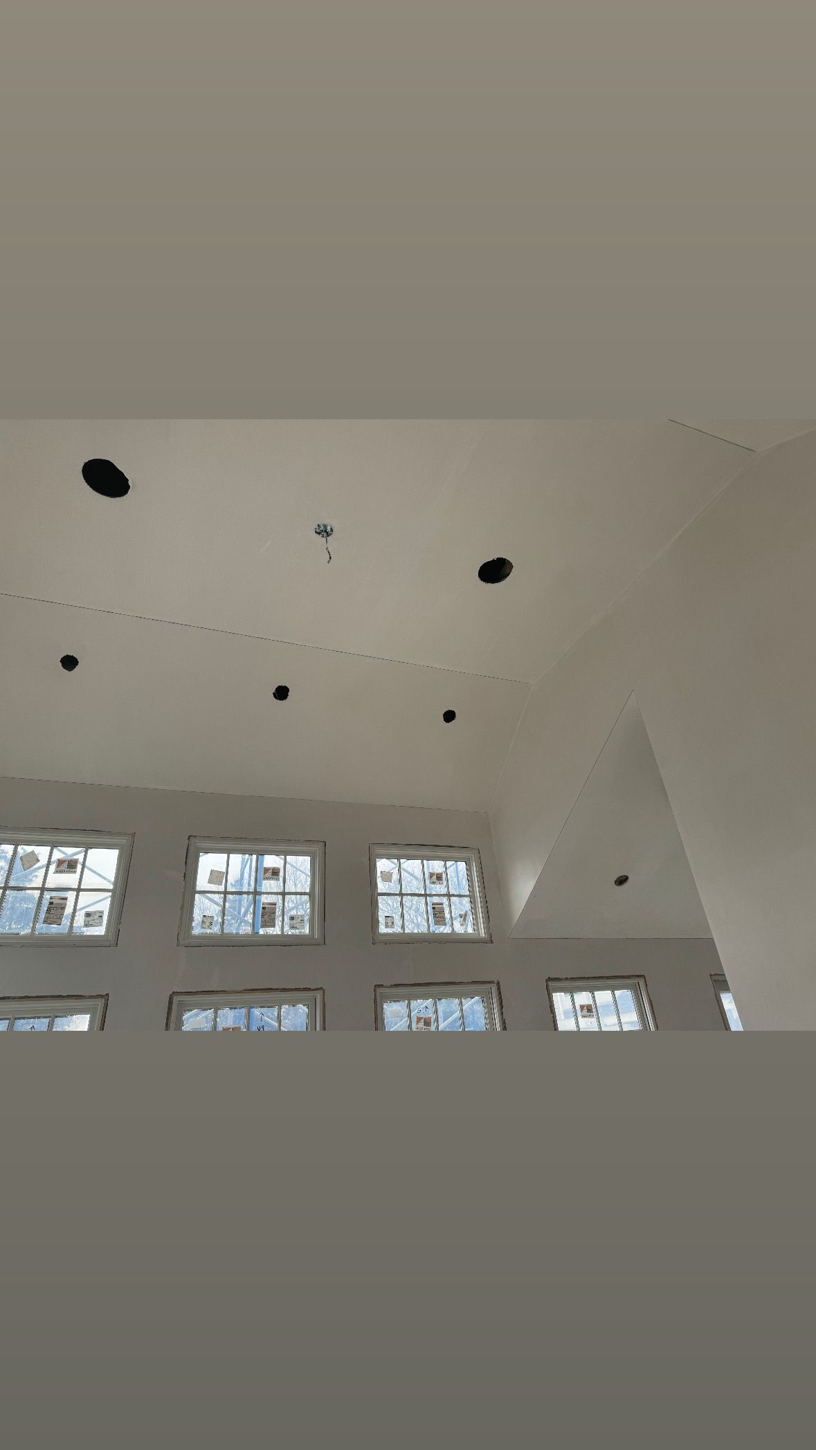 White interior ceiling with recessed black lights and a row of small windows below.