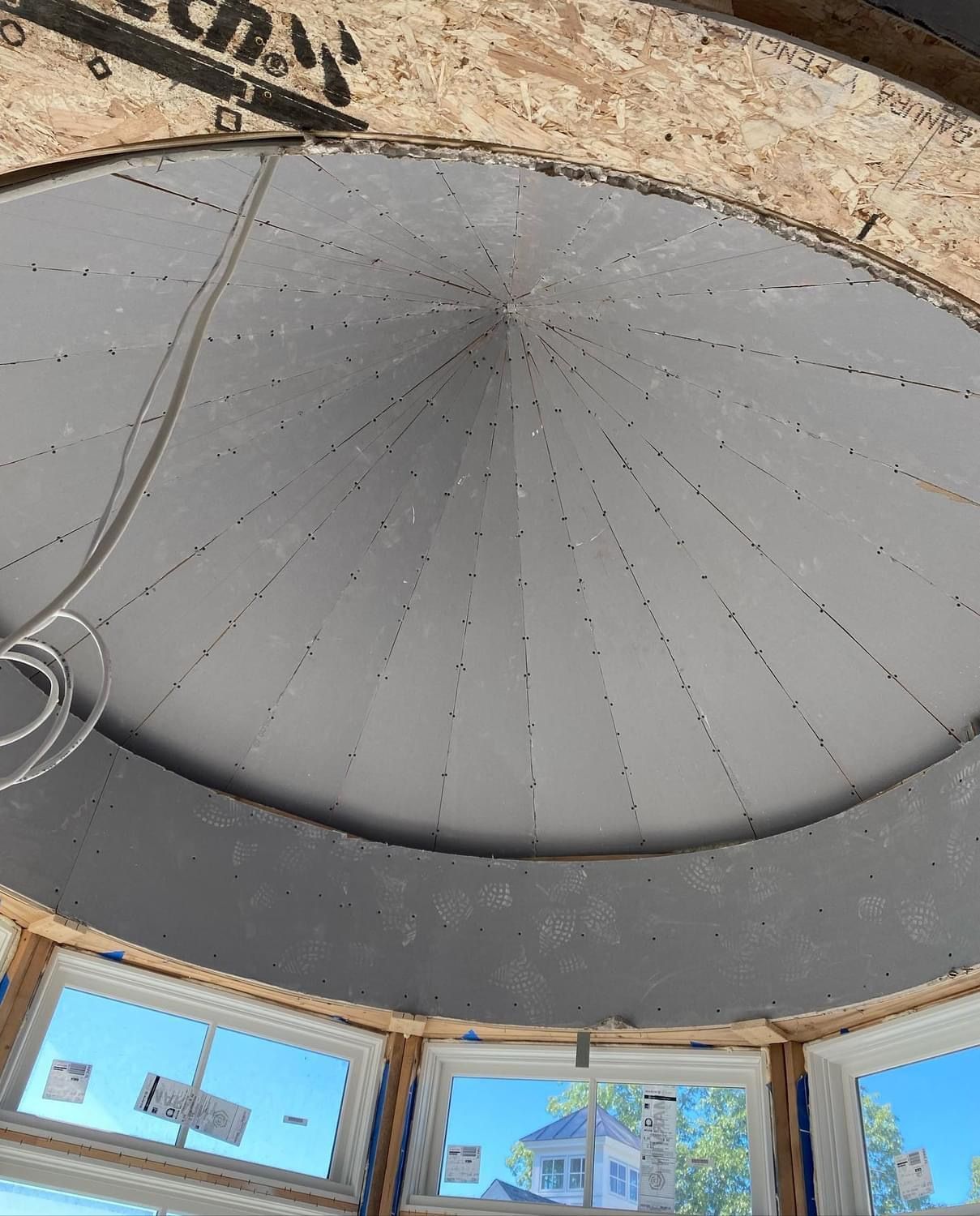 Interior view of a dome ceiling with white radial panels above windows and rough stone edges