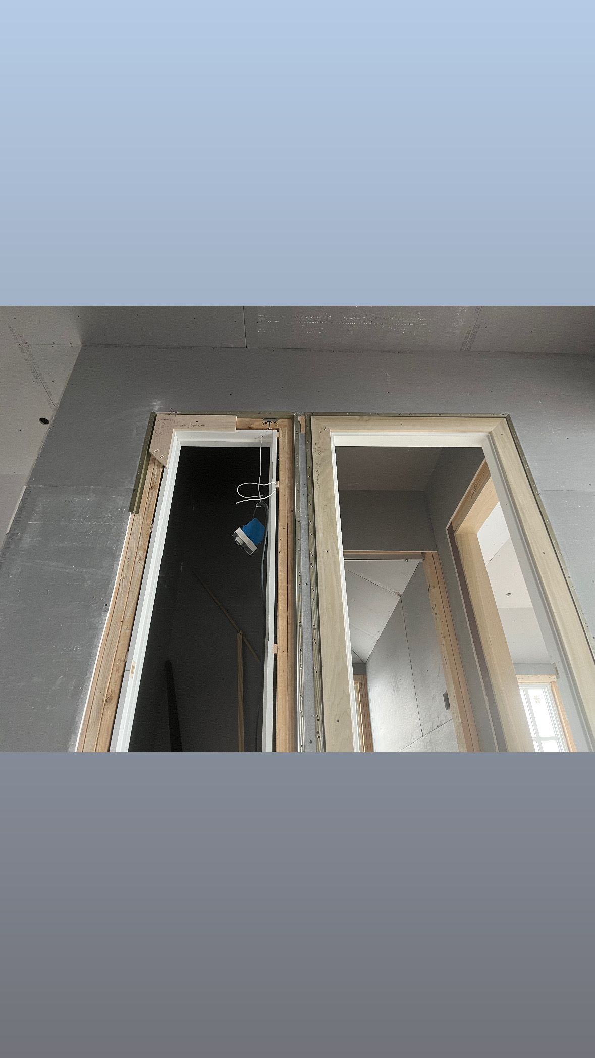 Partially open beige window in a gray wall beneath a blue sky