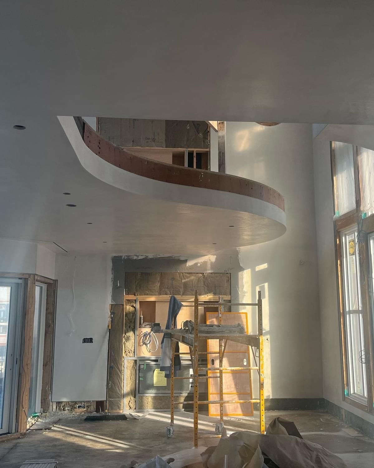 Interior under renovation with scaffolding, tall windows, and a curved ceiling feature under construction