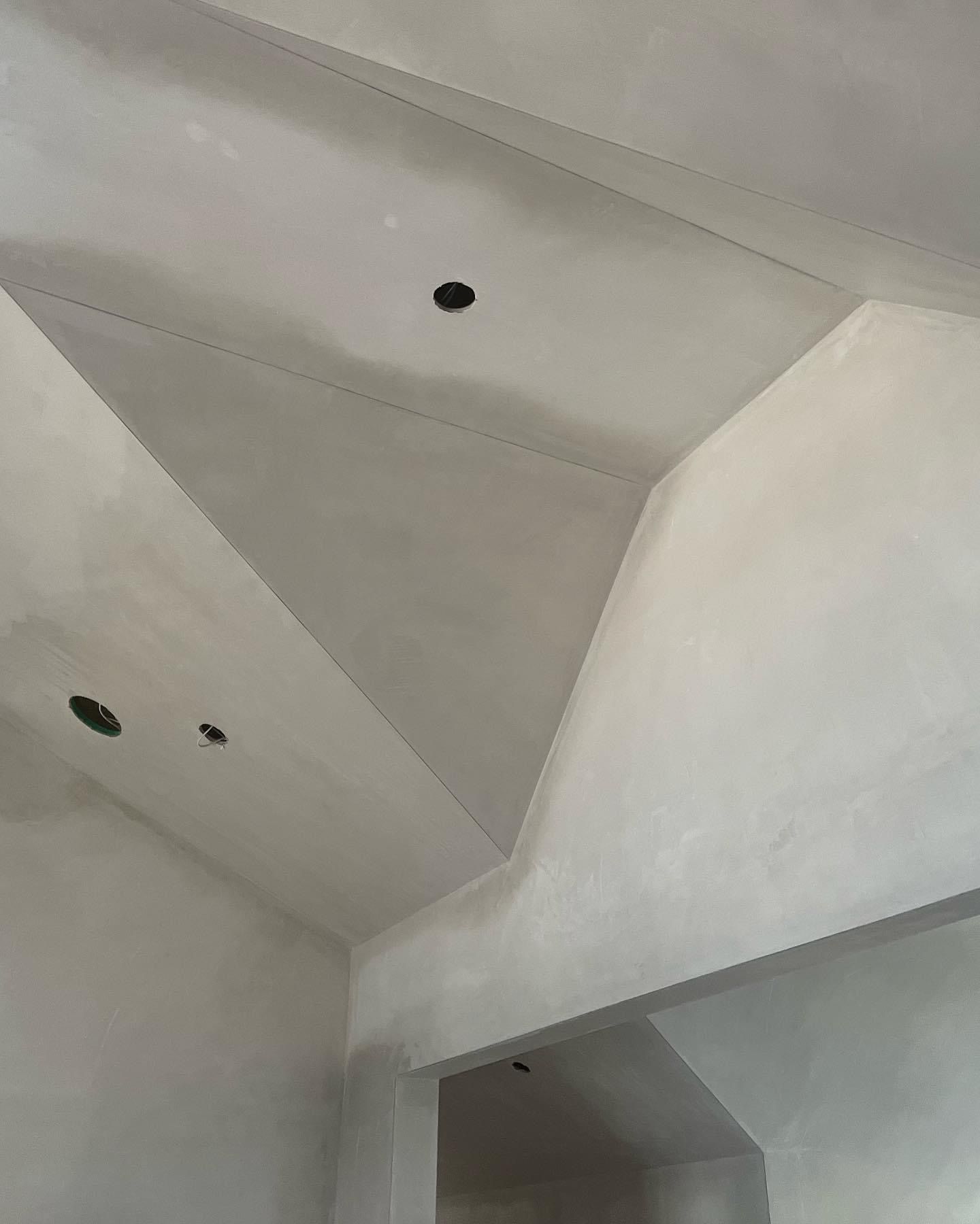 White unfinished ceiling and walls with recessed light holes above an open doorway