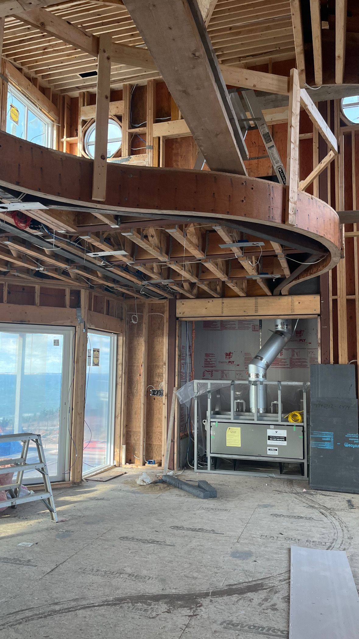 Interior of a partially demolished building with exposed framing, spiral staircase, and construction equipment.