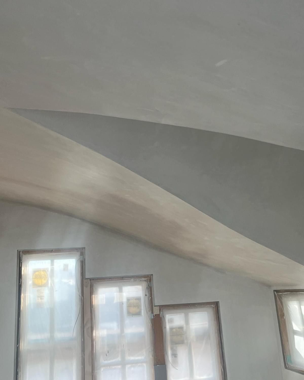 Sloped gray ceiling above several windows covered with white sheers in a bright room