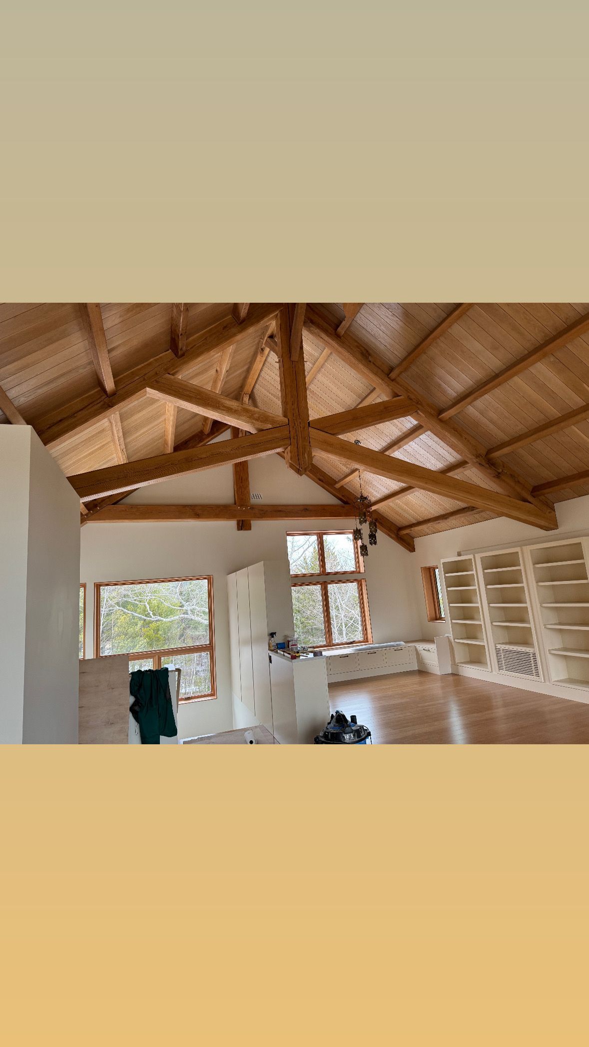 Unfinished room with exposed wooden roof beams, windows, and shelves along the wall